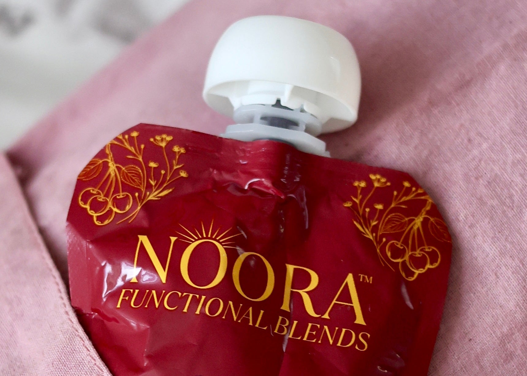 Red pouch labeled 'Noora Functional Blends Calm' on a yoga bag pink fabric background