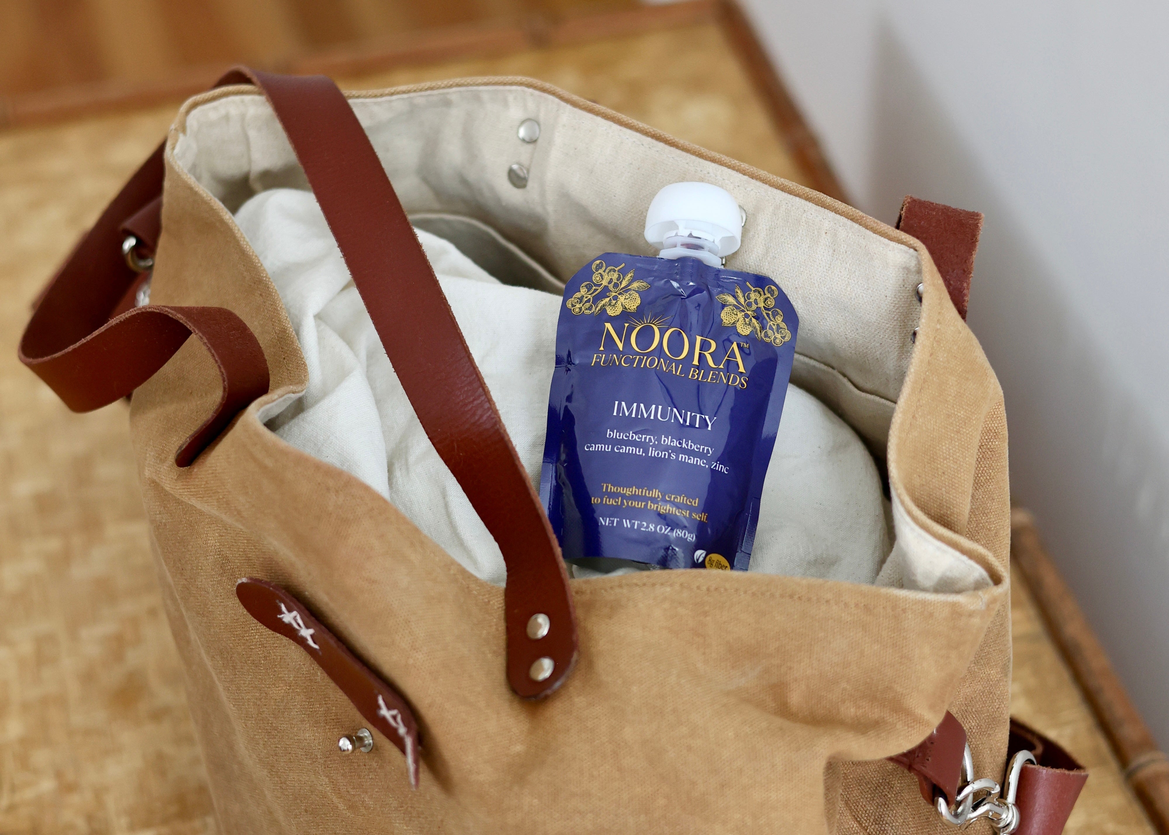 Brown leather bag with a blue pouch of Noora Immunity Functional Blends.